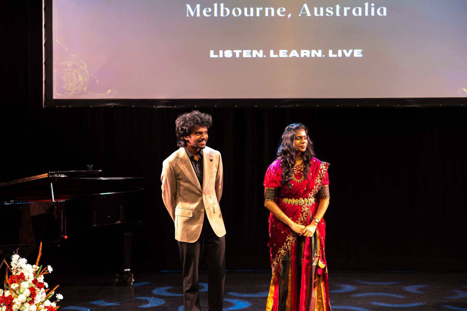 Hosts on stage under a screen reading Melbourne, Australia