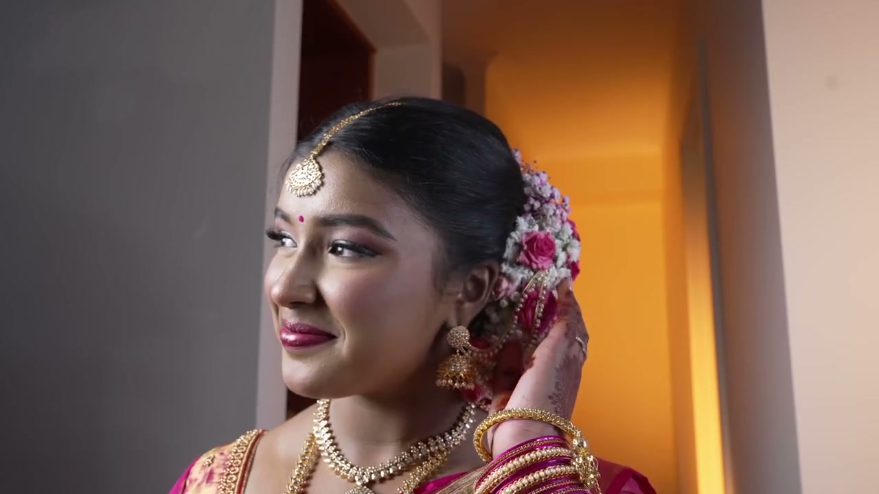 A young woman in a pink silk saree smiling at her saree ceremony